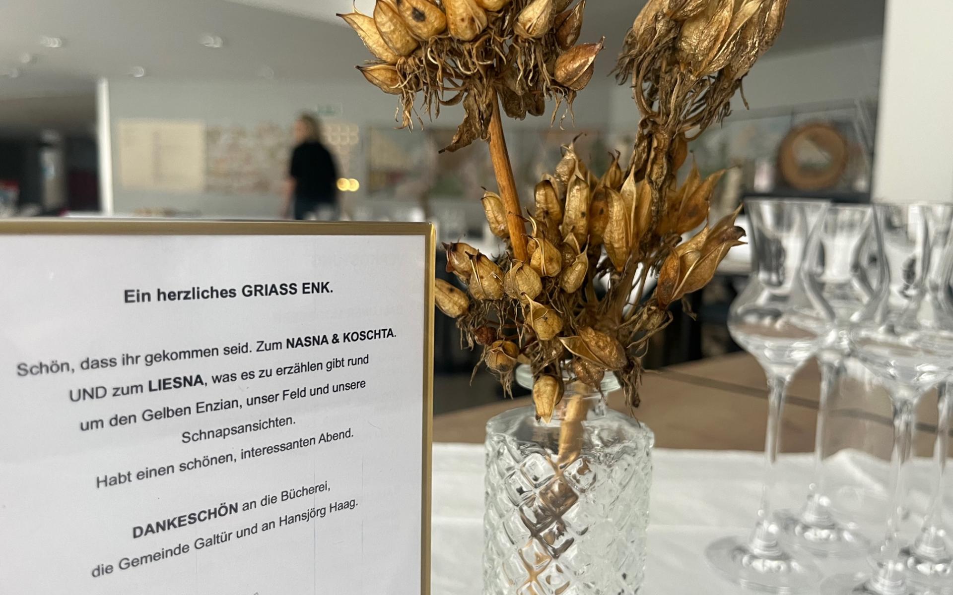 Kleine Vase mit getrockneten Enzianblüten, Austeller mit Einladungstext.